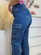 Extra rugalmas anyagú, magas derekú, oldalzsebes, egyenes szárú farmernadrág. A Modell S méretet visel. (XS-XL méretekben.)