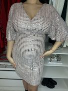 Csillogós, A vonalú, V kivágású, hátán cipzáras, nem rugalmas, alkalmi ruha. A Modell 36-os méretet visel.